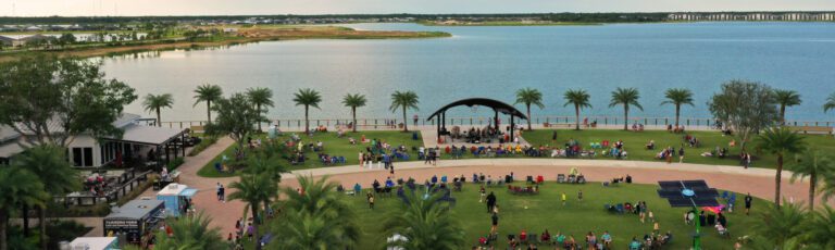 Events | Babcock Ranch aerial image of band playing under bandshell to crowd on green lawn